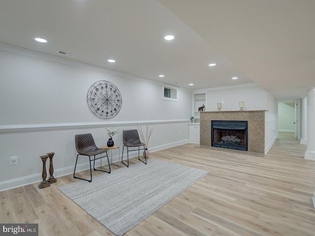 sitting room featuring crown molding, light hardwood / wood-style flooring, and a high end fireplace