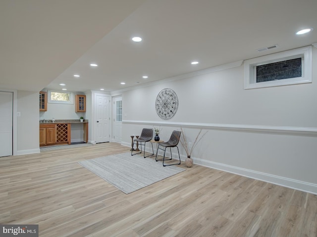 living area with crown molding and light hardwood / wood-style floors