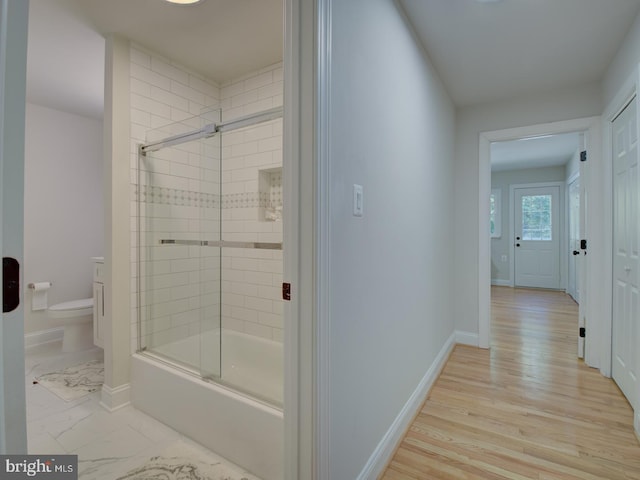 bathroom featuring bath / shower combo with glass door, hardwood / wood-style floors, and toilet