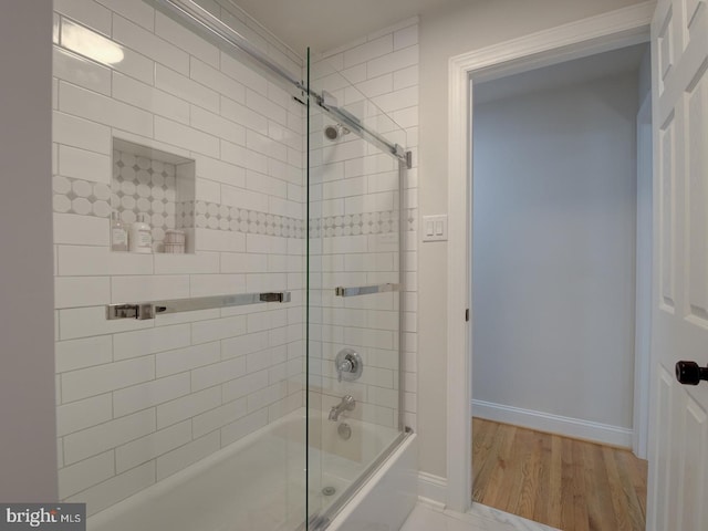 bathroom featuring wood-type flooring and combined bath / shower with glass door