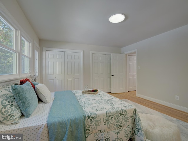 bedroom featuring multiple closets and light hardwood / wood-style flooring