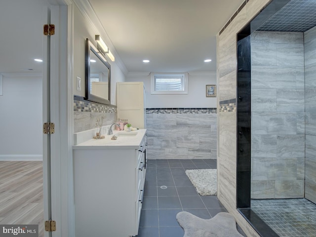 bathroom with tile patterned floors, crown molding, tile walls, a tile shower, and vanity