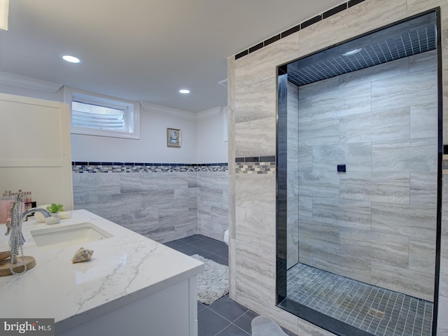 bathroom featuring tile walls, tiled shower, vanity, ornamental molding, and tile patterned floors