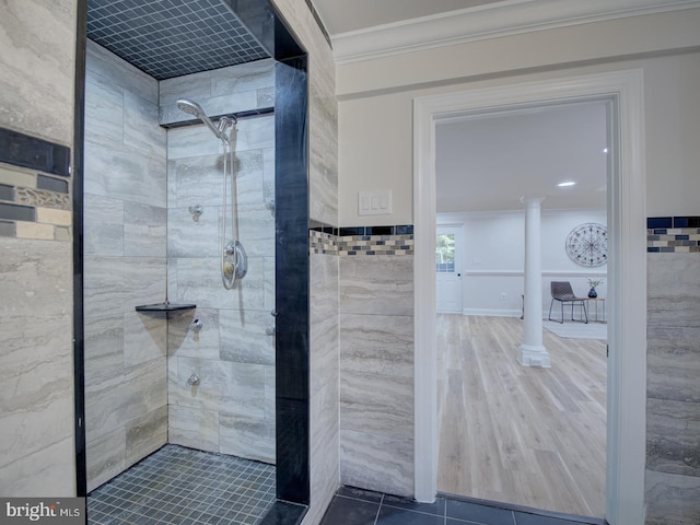 bathroom featuring ornate columns, ornamental molding, tile walls, and a tile shower