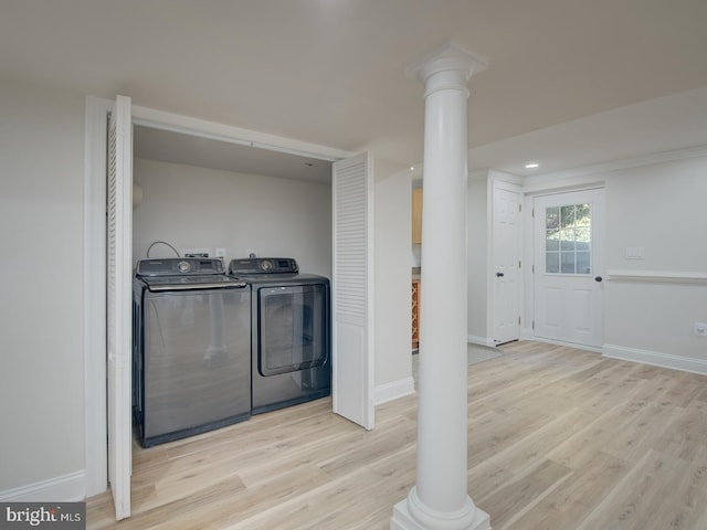 laundry area with decorative columns, washer and dryer, and light wood-type flooring