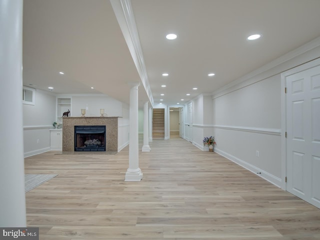 unfurnished living room featuring crown molding, built in features, light hardwood / wood-style floors, and decorative columns