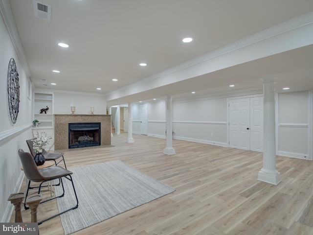 living room featuring a premium fireplace, ornamental molding, decorative columns, and light hardwood / wood-style floors