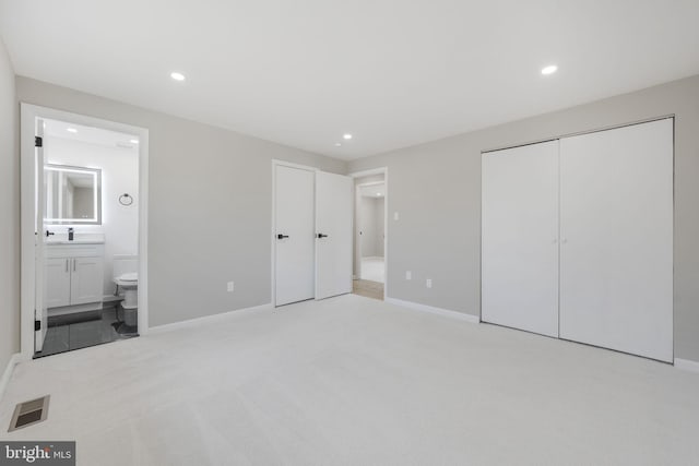 unfurnished bedroom featuring connected bathroom, light colored carpet, and a closet