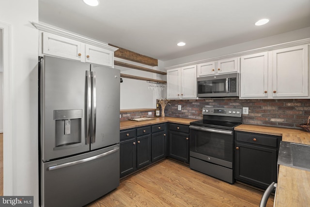 kitchen featuring white cabinetry, wooden counters, decorative backsplash, stainless steel appliances, and light wood-type flooring