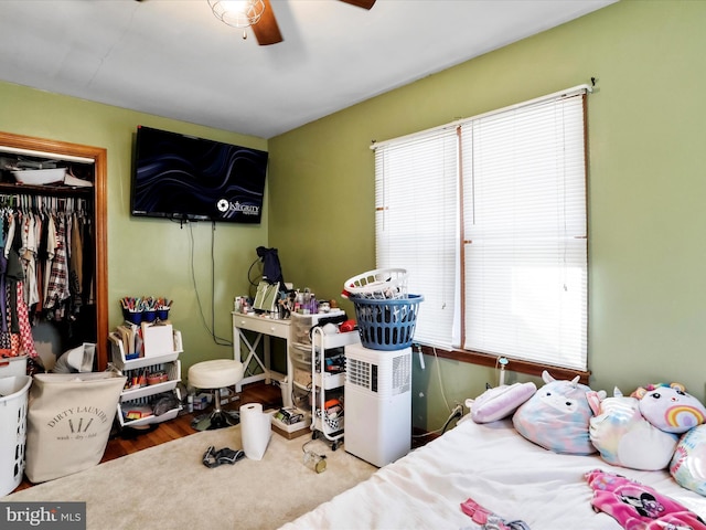 bedroom featuring ceiling fan, a closet, hardwood / wood-style floors, and multiple windows