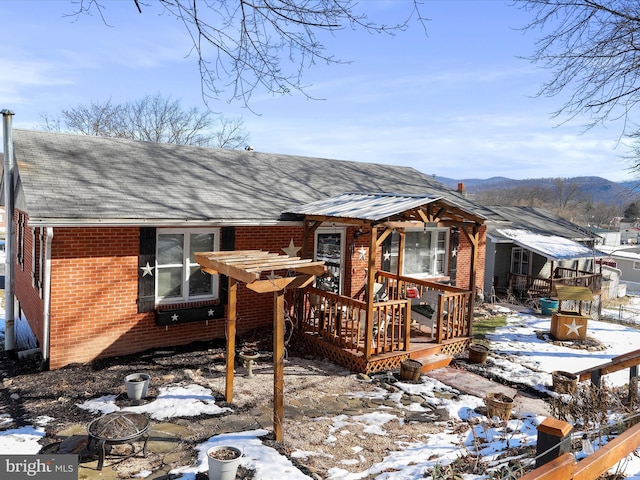 snow covered back of property featuring a deck with mountain view