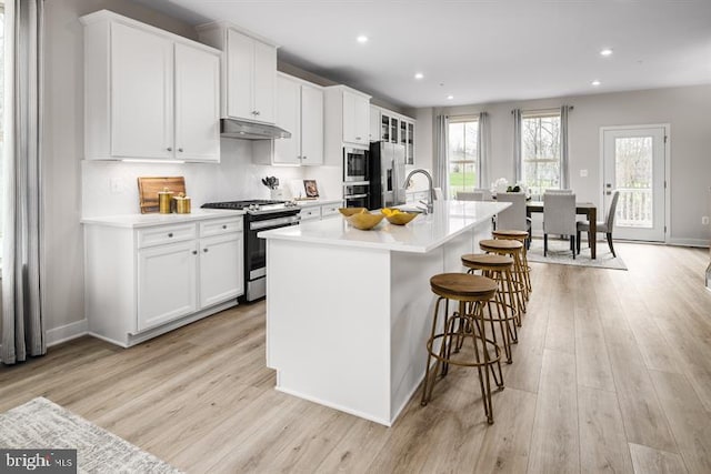 kitchen featuring a center island with sink, light hardwood / wood-style floors, white cabinets, and appliances with stainless steel finishes