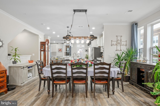 dining area featuring light wood finished floors, visible vents, ornamental molding, and recessed lighting