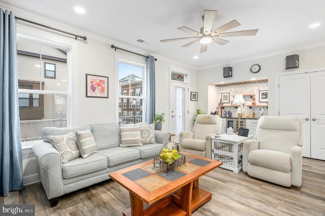 living area with ornamental molding, visible vents, and light wood-style floors