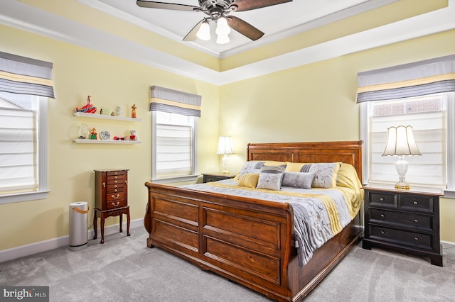 bedroom with a raised ceiling, ornamental molding, a ceiling fan, carpet flooring, and baseboards