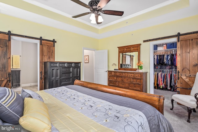 carpeted bedroom with a tray ceiling, a barn door, and a closet