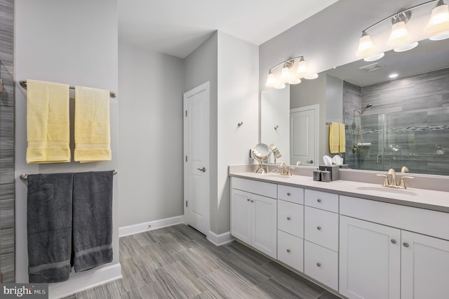 full bath featuring a stall shower, a sink, baseboards, and double vanity