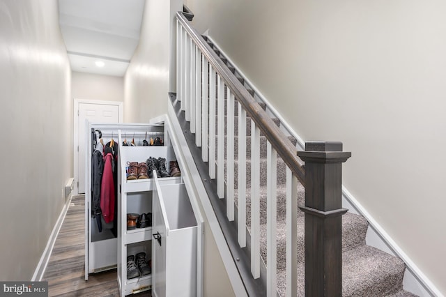 staircase featuring wood finished floors and baseboards