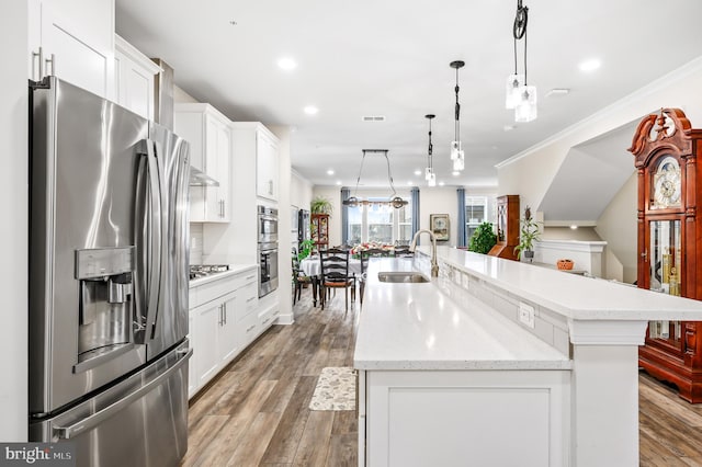 kitchen with a spacious island, sink, appliances with stainless steel finishes, pendant lighting, and white cabinets