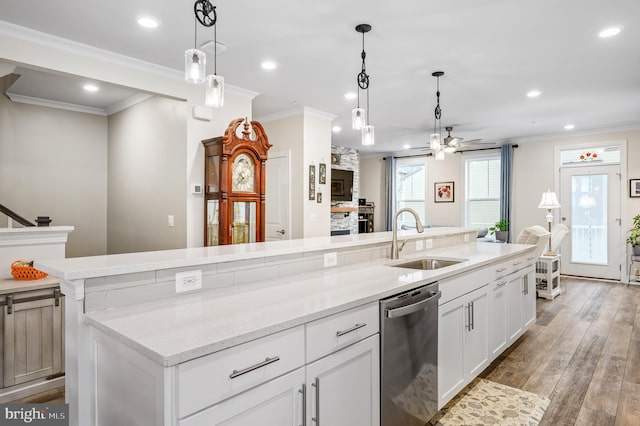 kitchen featuring stainless steel dishwasher, ornamental molding, white cabinets, a sink, and wood finished floors