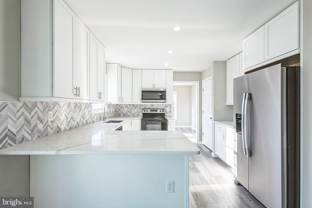 kitchen featuring appliances with stainless steel finishes, kitchen peninsula, sink, and white cabinets