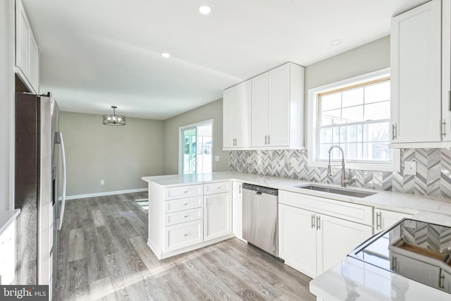 kitchen featuring sink, white cabinetry, hanging light fixtures, stainless steel appliances, and kitchen peninsula