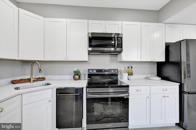 kitchen with white cabinetry, sink, light stone counters, and stainless steel appliances