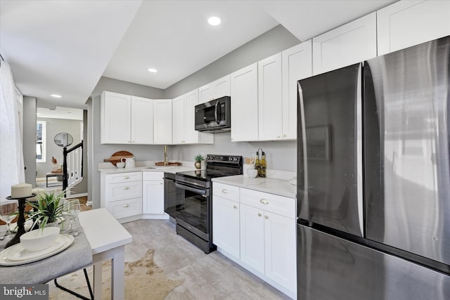 kitchen featuring white cabinetry, black electric range oven, light stone counters, and stainless steel refrigerator