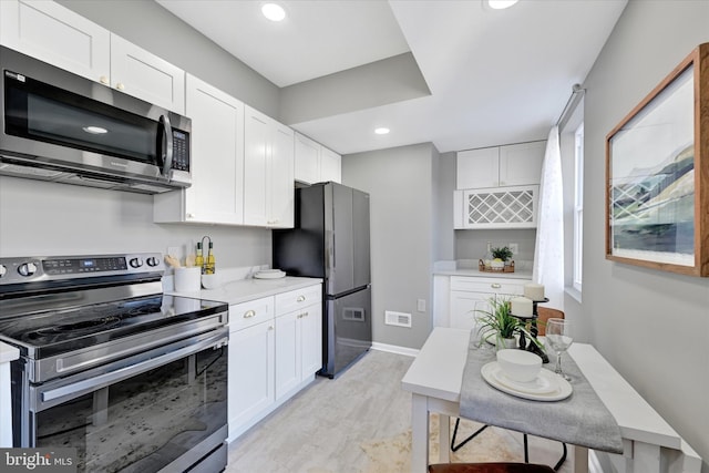 kitchen with stainless steel appliances, light hardwood / wood-style flooring, and white cabinets