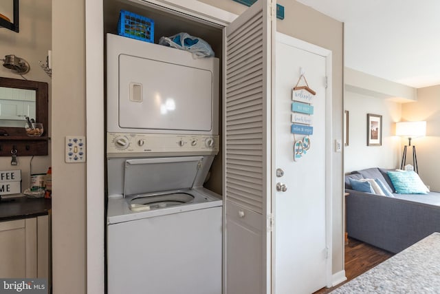 laundry room featuring stacked washer / drying machine and dark hardwood / wood-style floors