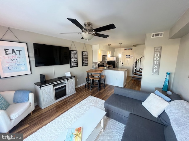 living room featuring dark wood-type flooring and ceiling fan