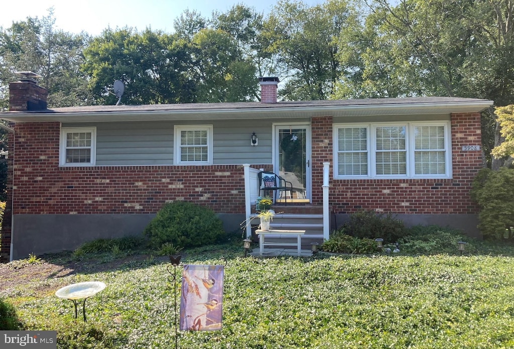 bungalow-style home with a chimney, a front lawn, and brick siding