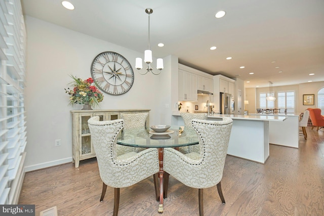 dining space featuring sink, hardwood / wood-style floors, and a chandelier