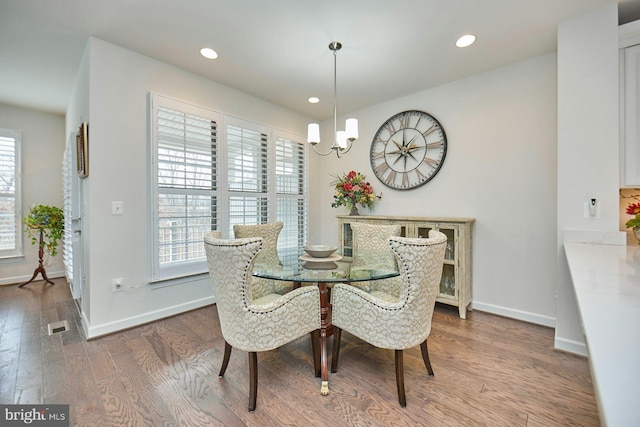 dining space with hardwood / wood-style flooring and a notable chandelier