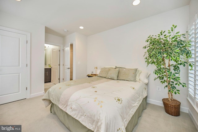 bedroom featuring connected bathroom and light carpet