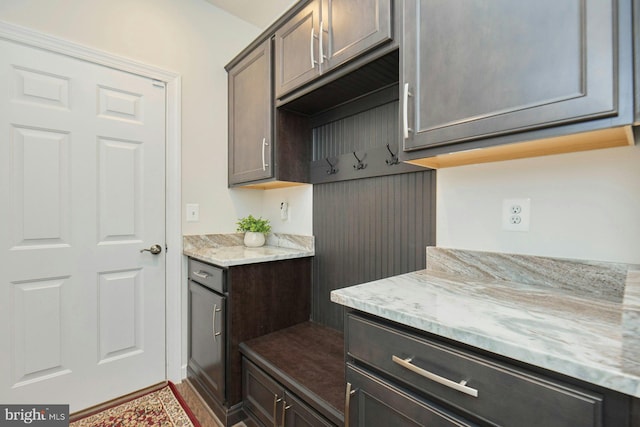 kitchen featuring dark brown cabinets and light stone counters