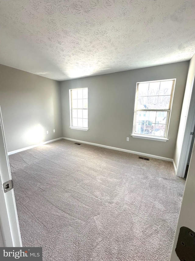 carpeted empty room featuring a textured ceiling