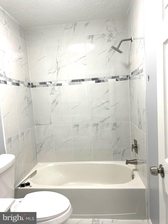 bathroom featuring toilet, tiled shower / bath combo, and a textured ceiling