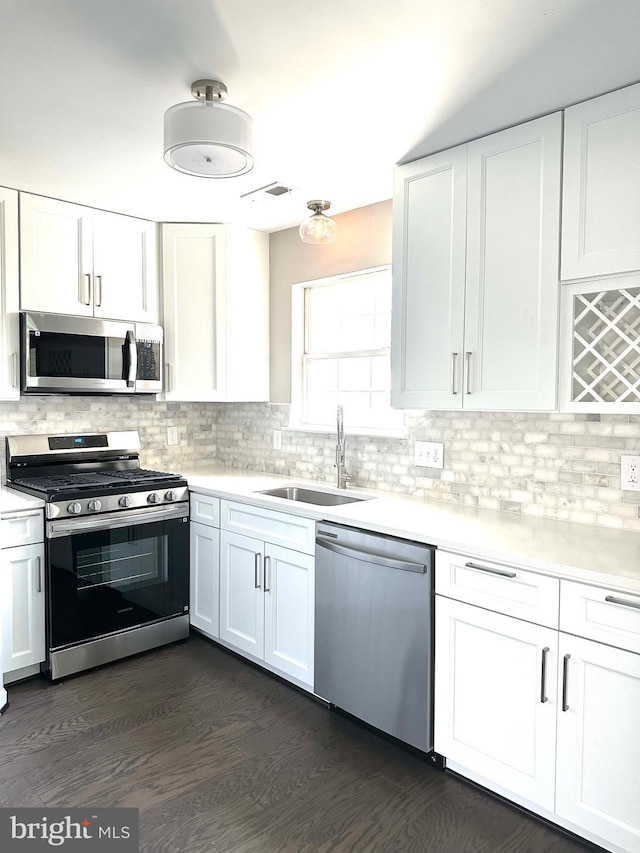 kitchen featuring dark hardwood / wood-style floors, white cabinetry, sink, decorative backsplash, and stainless steel appliances