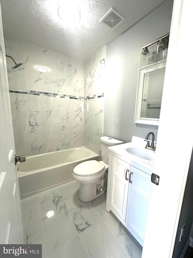 full bathroom with vanity, tiled shower / bath combo, toilet, and a textured ceiling