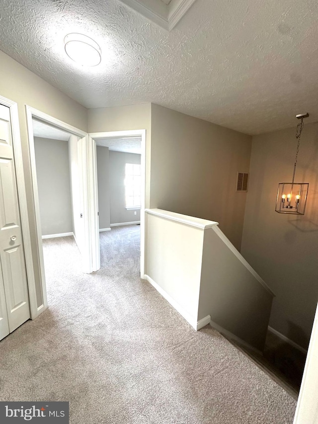 hall featuring light colored carpet and a textured ceiling