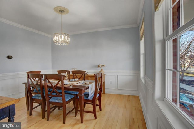 dining area with crown molding, a chandelier, and light wood-type flooring