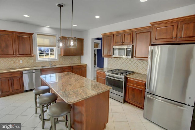 kitchen featuring sink, a breakfast bar area, a center island, hanging light fixtures, and appliances with stainless steel finishes