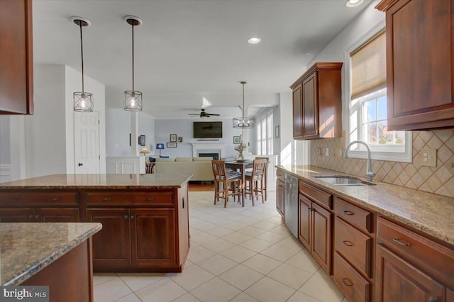 kitchen with decorative light fixtures, dishwasher, sink, and light stone countertops