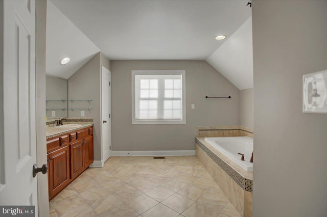 bathroom with vanity, lofted ceiling, and tiled bath