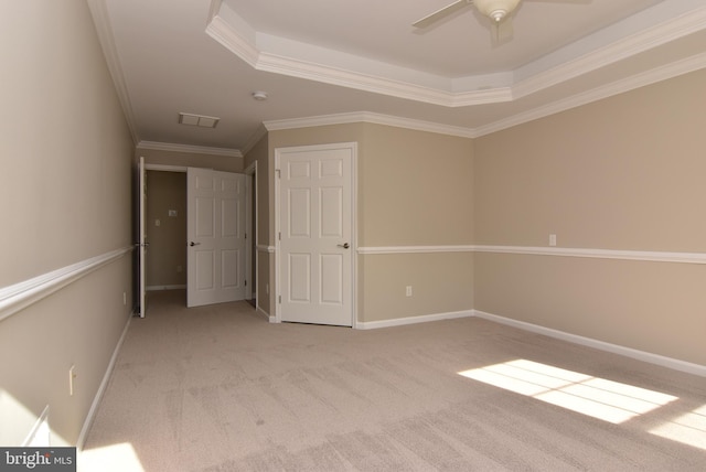 unfurnished bedroom with ceiling fan, ornamental molding, a raised ceiling, and light carpet