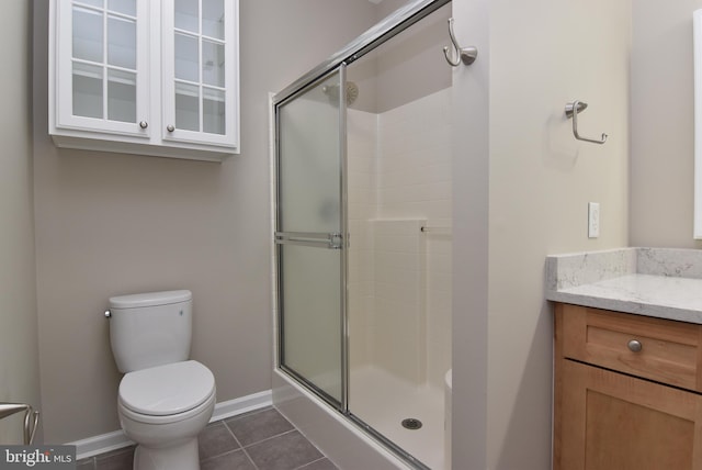 bathroom featuring tile patterned flooring, vanity, toilet, and walk in shower