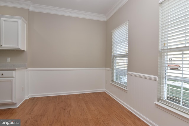 unfurnished dining area featuring ornamental molding and light hardwood / wood-style flooring