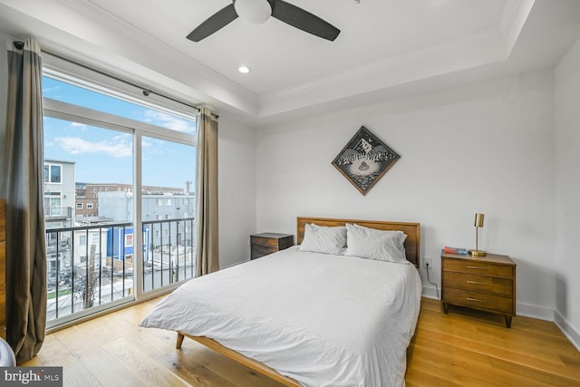 bedroom with ornamental molding, light wood-style flooring, a tray ceiling, baseboards, and access to exterior