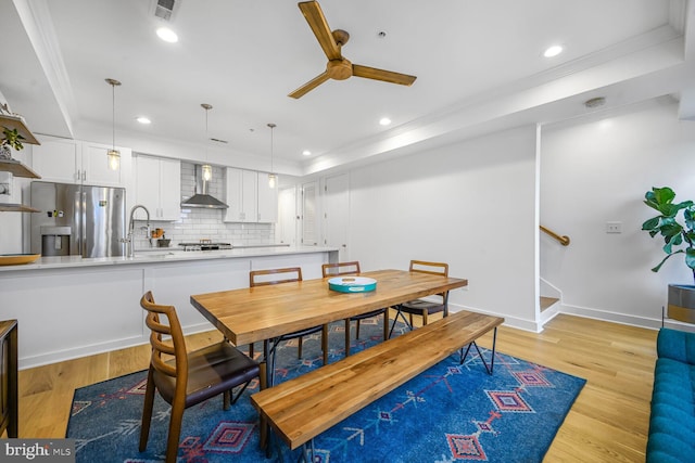 dining room featuring light wood finished floors, stairway, recessed lighting, and a raised ceiling